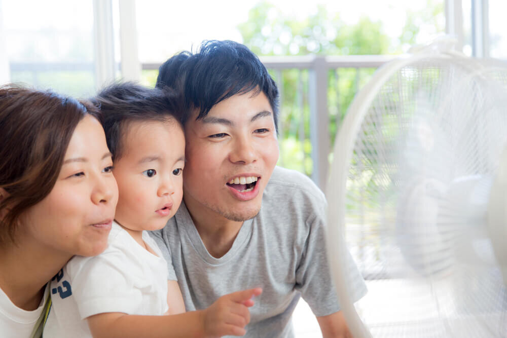 扇風機の風にあたる親子