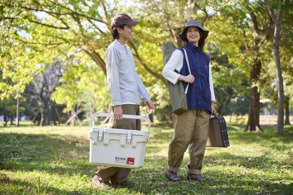 アウトドアでクーラーボックスを持ち運ぶ男性