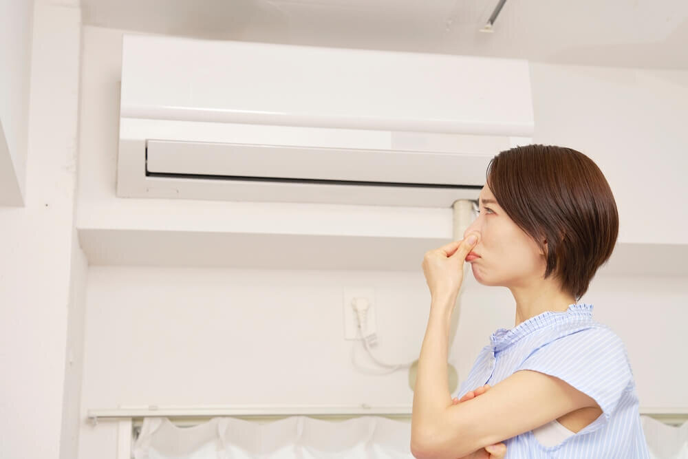 エアコンの前で鼻を押さえる女性