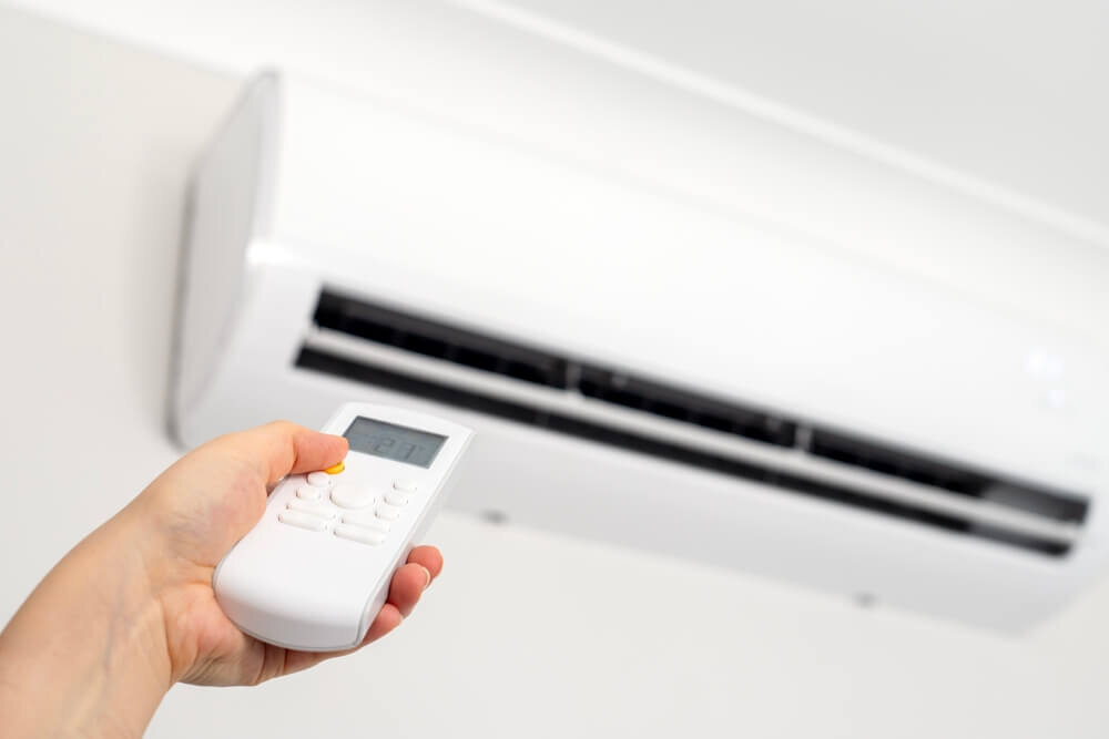 エアコンのリモコンを操作する人の手