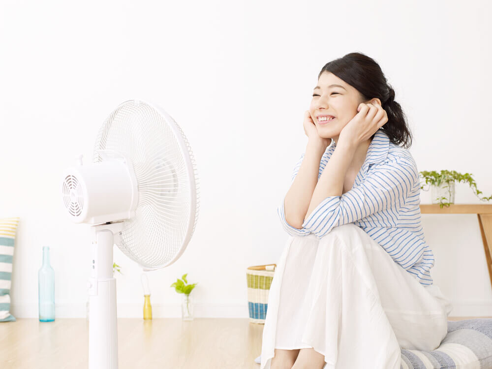 扇風機を使って涼む女性
