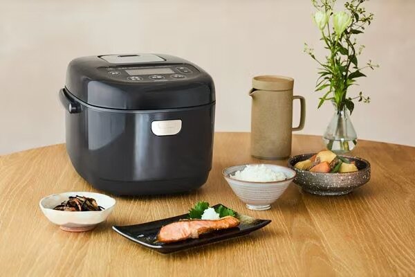 食卓に置かれた黒の炊飯器と料理