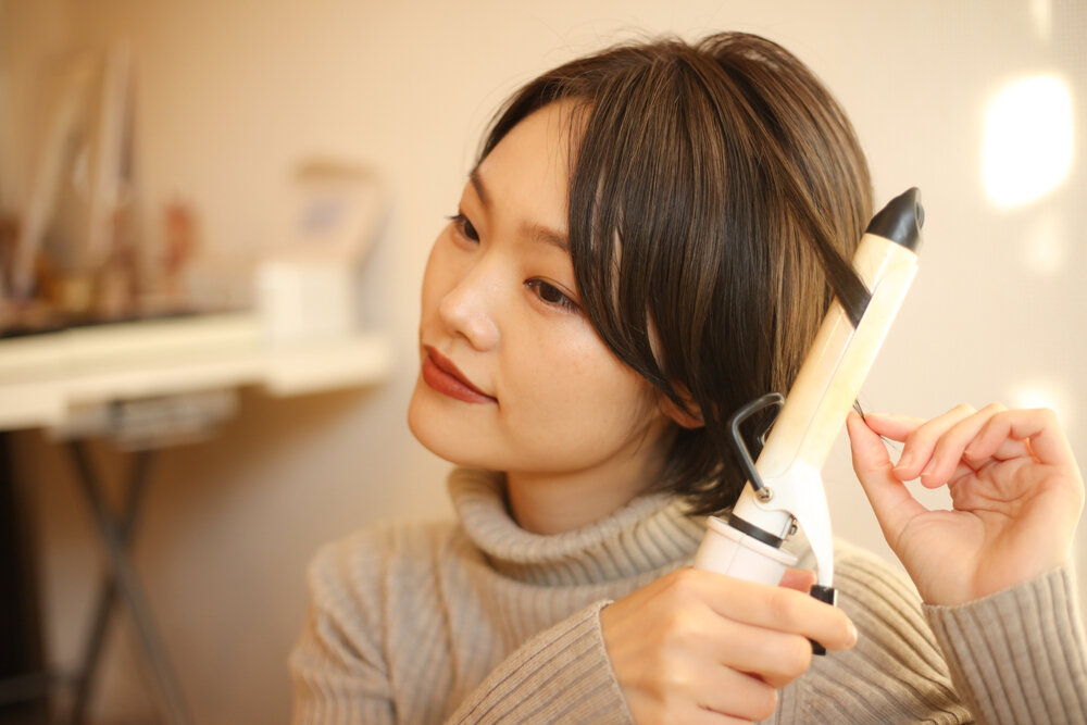 ヘアアイロンでセットする女性