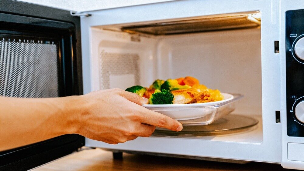 電子レンジで食べ物を温める人の手