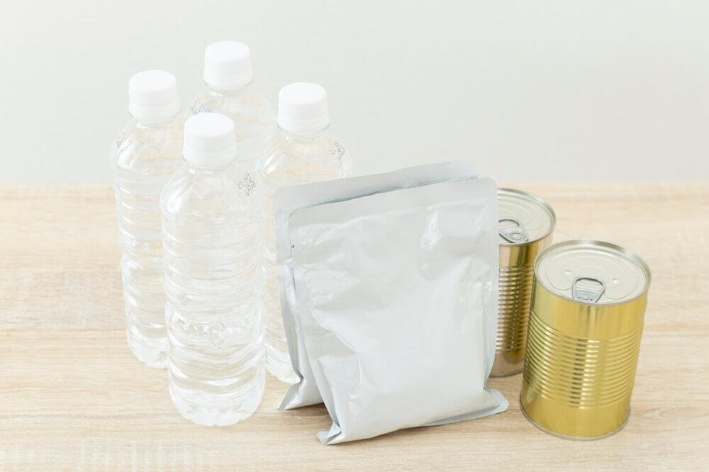 テーブルに置かれた水とレトルト食品と缶詰