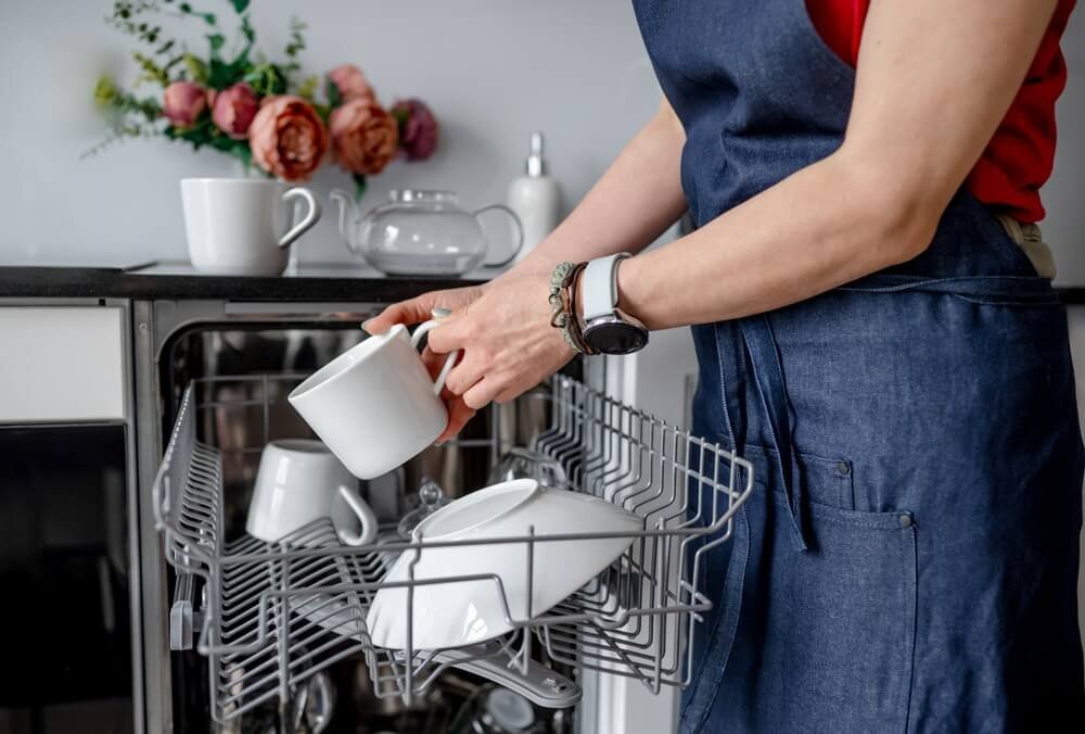食洗機に食器を入れる女性