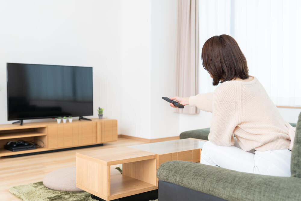 テレビをつけようとする女性の後ろ姿