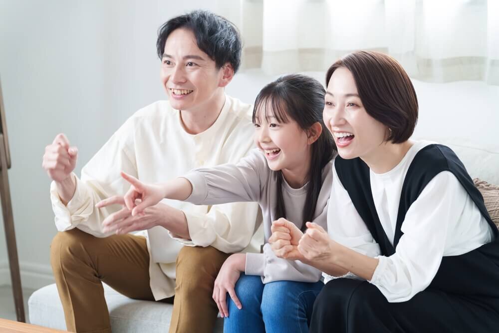 ソファに座ってテレビを見る家族