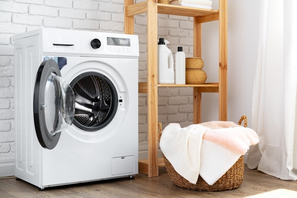 扉が開けっぱなしの洗濯機と洗濯物が入ったカゴ