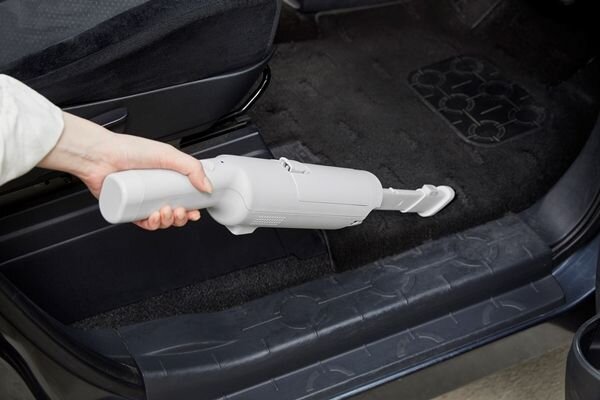 アイリスオーヤマのハンディクリーナーで車内を掃除する人