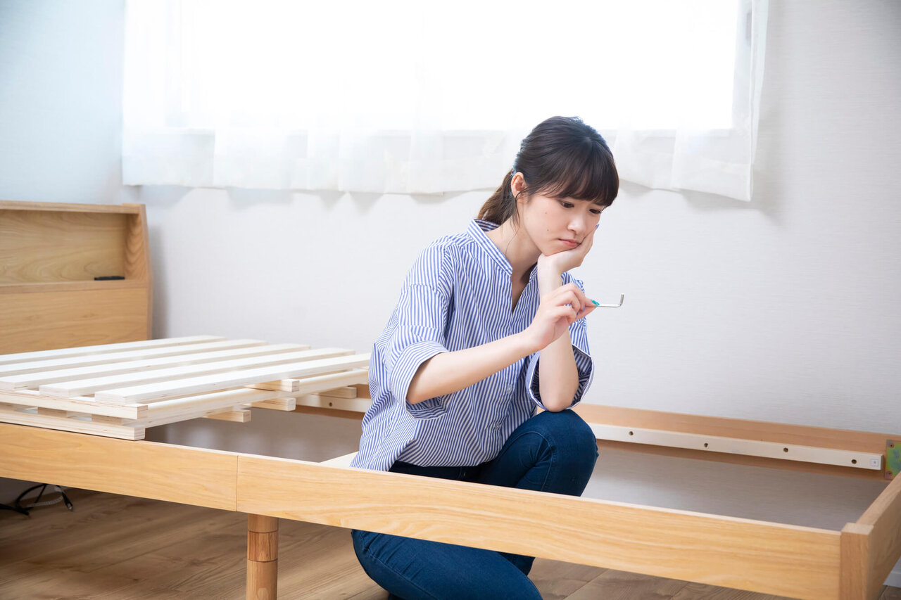 すのこベッドの組み立てに悩む女性