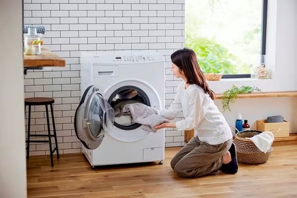 アイリスオーヤマのドラム式洗濯機で洗濯する女性