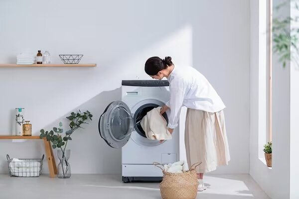 アイリスオーヤマのドラム式洗濯機から洗濯物を取り出す女性