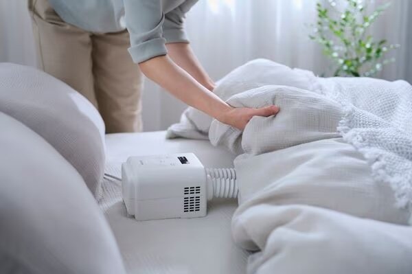 アイリスオーヤマのふとん乾燥機をふとんにセットする女性