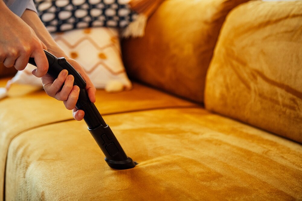 掃除器を使ってソファを掃除する手元