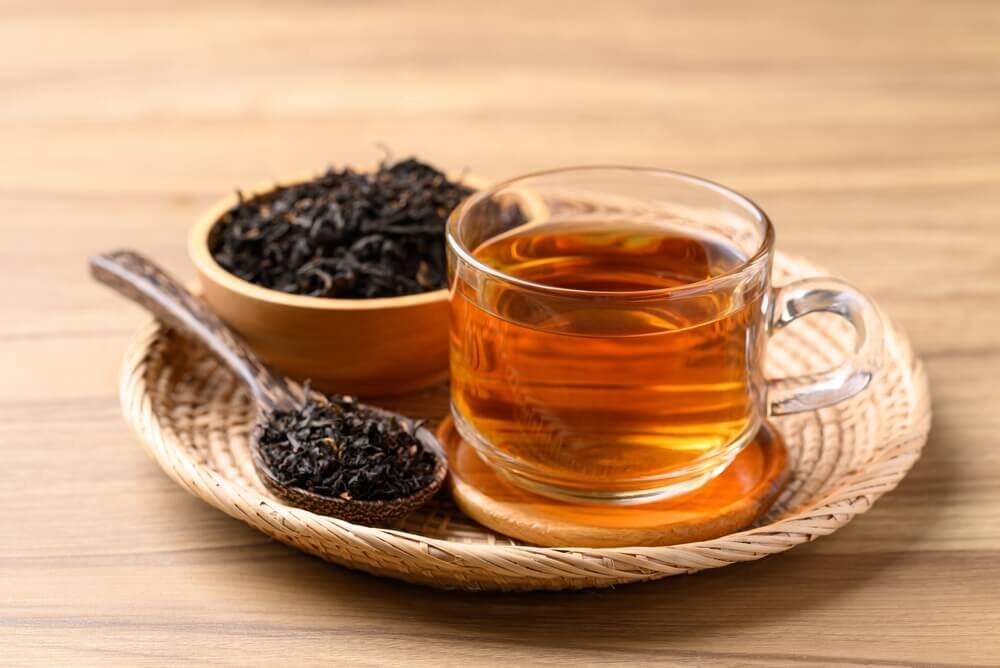 スプーンとお皿に盛られた茶葉と紅茶