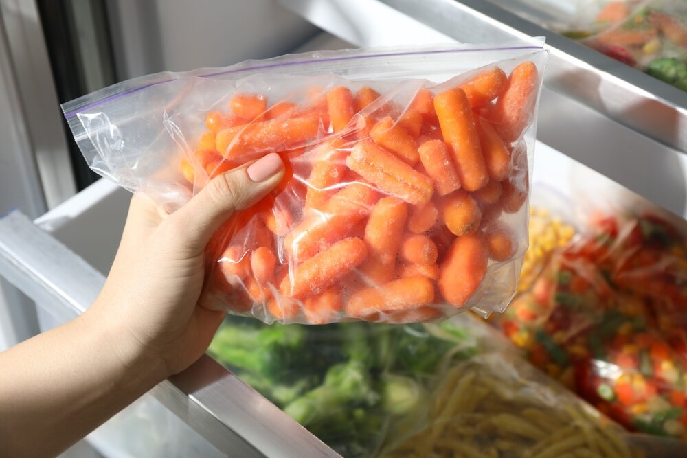 冷凍庫へ野菜を入れる手元