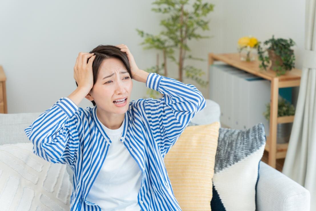 ソファーの上で頭を抱えている女性