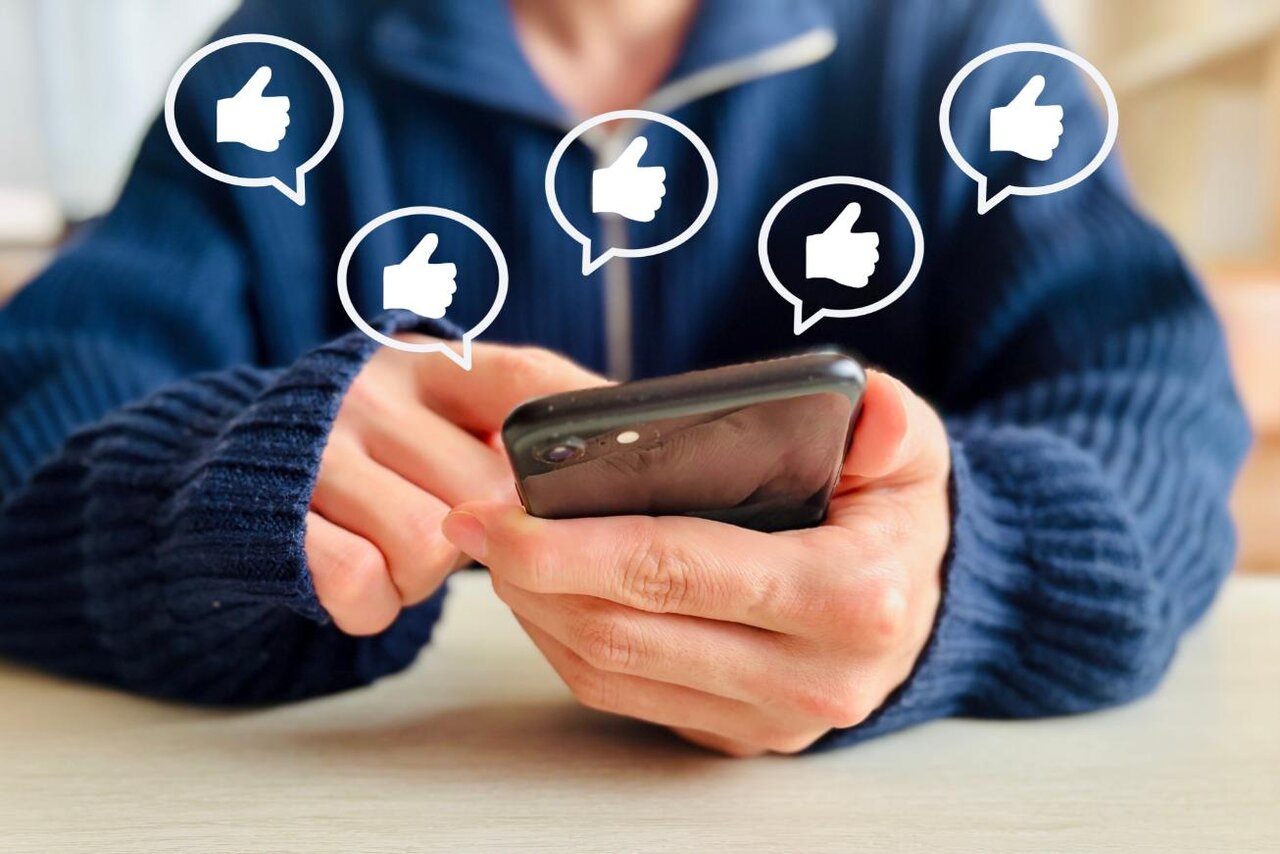 いいねのアイコンとスマホを操作している人