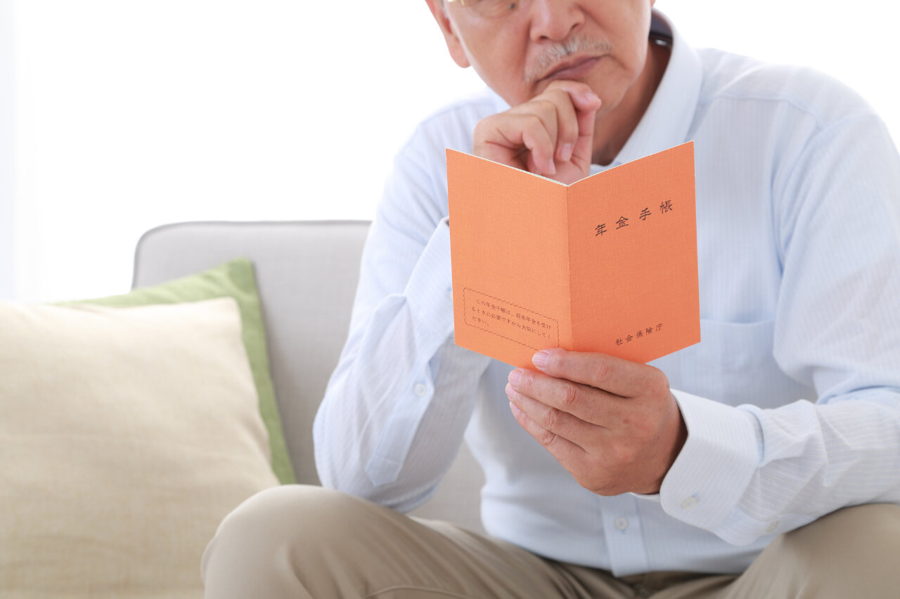 年金手帳を眺めるシニア男性