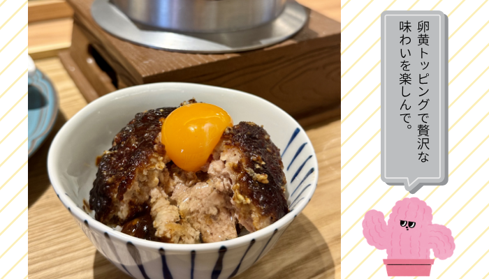 茶碗にご飯とハンバーグ、その上に卵黄がのっている