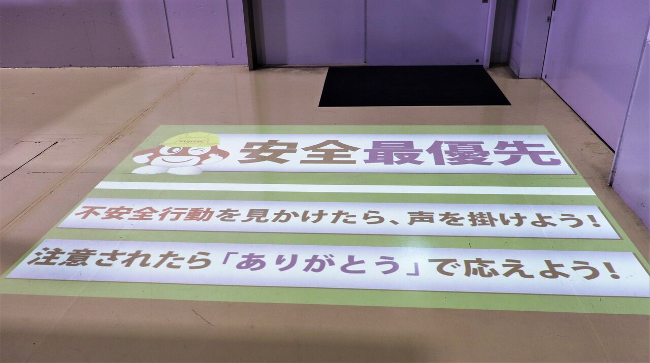 ロゴ投影ライトを使った工場入り口のデザインの一例。QC活動から生まれたアイデアで、工場見学のお出迎え、作業者への安全喚起などが映し出される