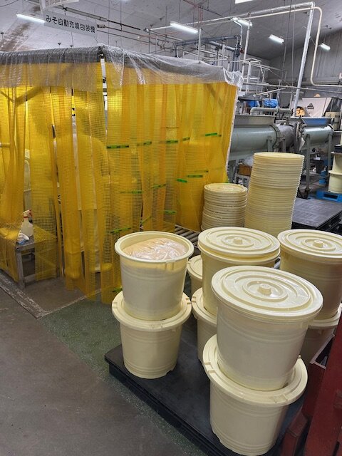 半自動化したみそ充填作業（充填・計量・樽詰め）とみそ樽 （写真提供：サクラみそ食品）