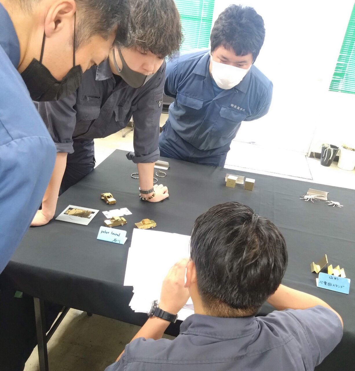 「技能向上プロジェクト」の一環として全社員が思い思いの作品を板金加工でつくった。写真は作品への意見交換会の様子（写真提供：葵製作所）