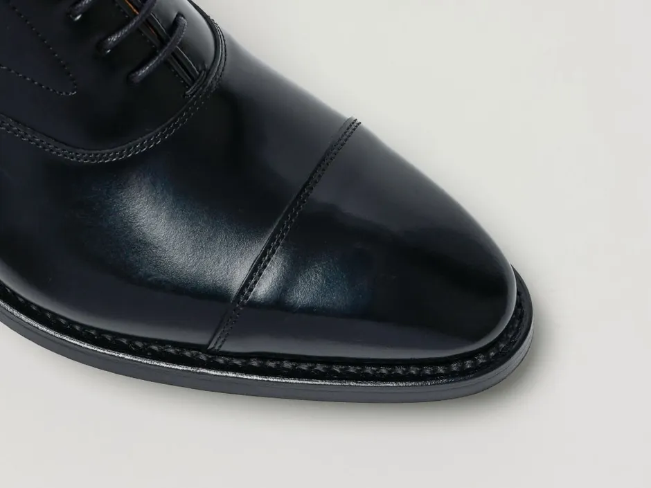 黒い革靴のクローズアップ写真。靴のつま先部分が写っており、光沢のある革の質感が際立っている。ステッチや靴底のディテールも確認できる。