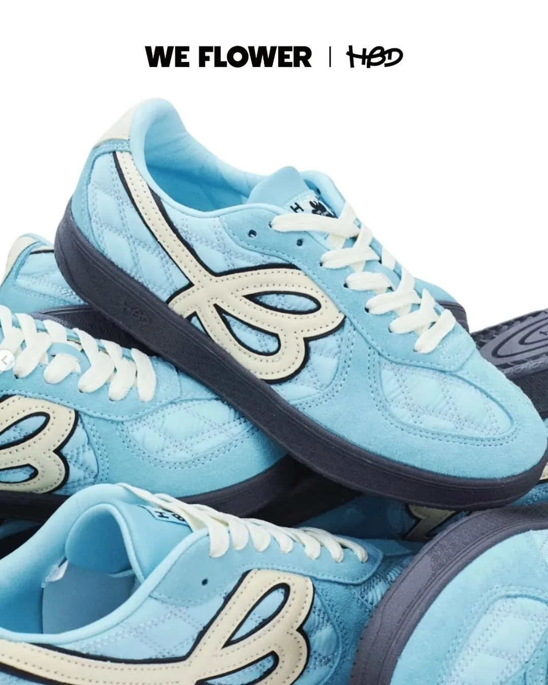 水色のスニーカーが積み重ねられた写真。白のロゴと紐、黒のソールが特徴。