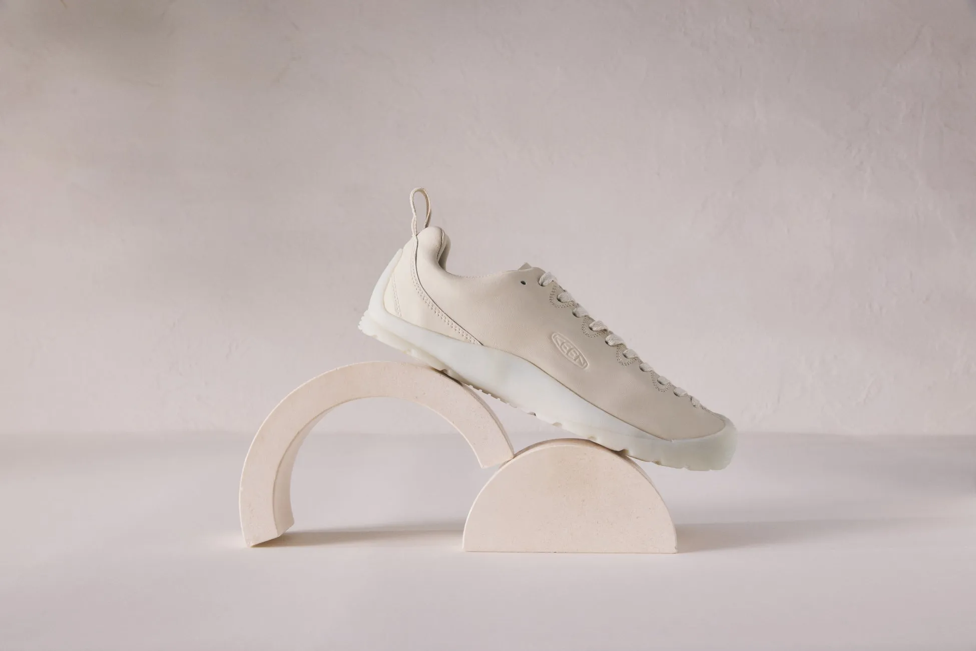 ベージュ色のKEENスニーカーが、半円柱のオブジェの上に置かれた、スタイリッシュな写真。