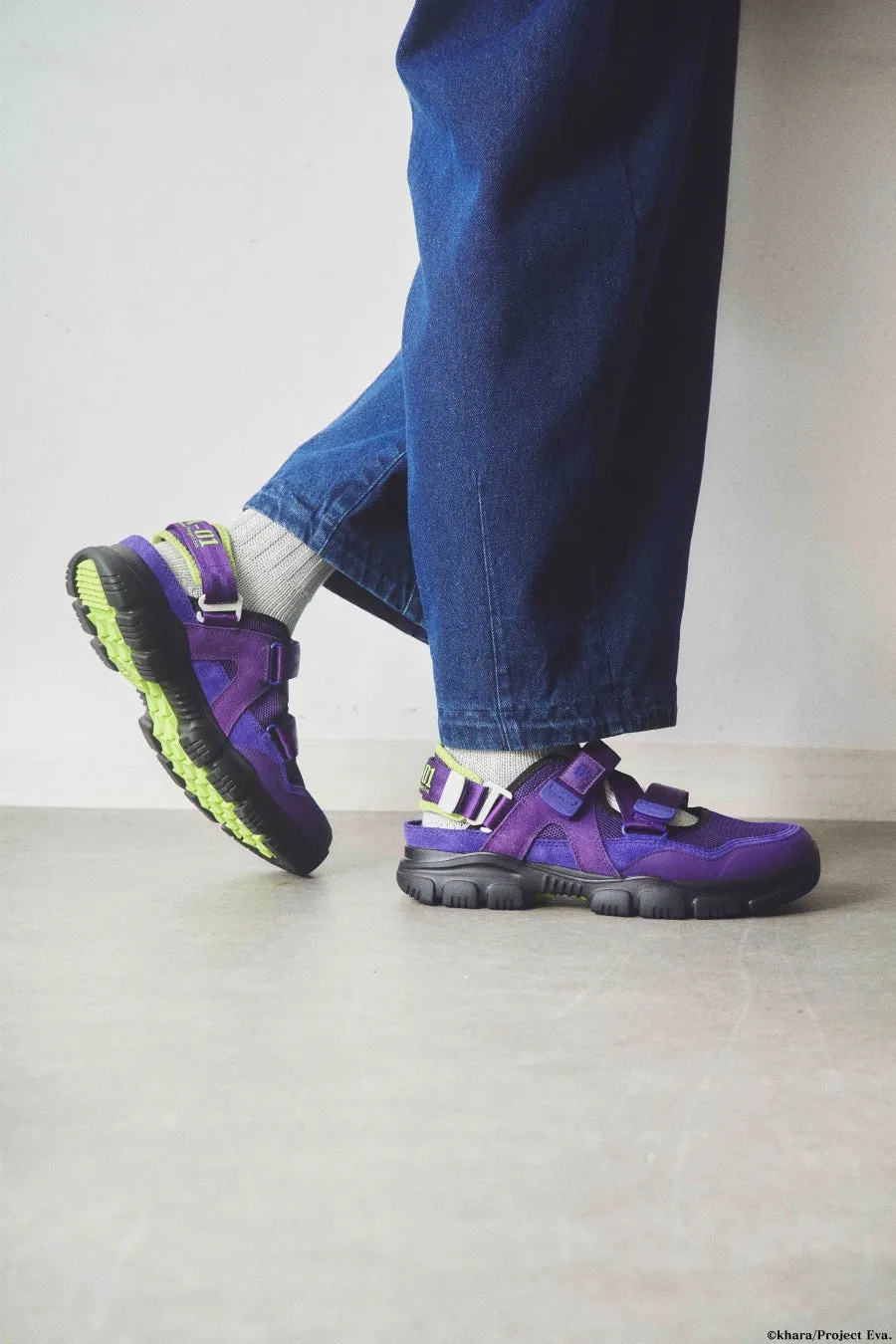 紫色のサンダルを履いた足元の写真です。ジーンズを履いた人が写っています。