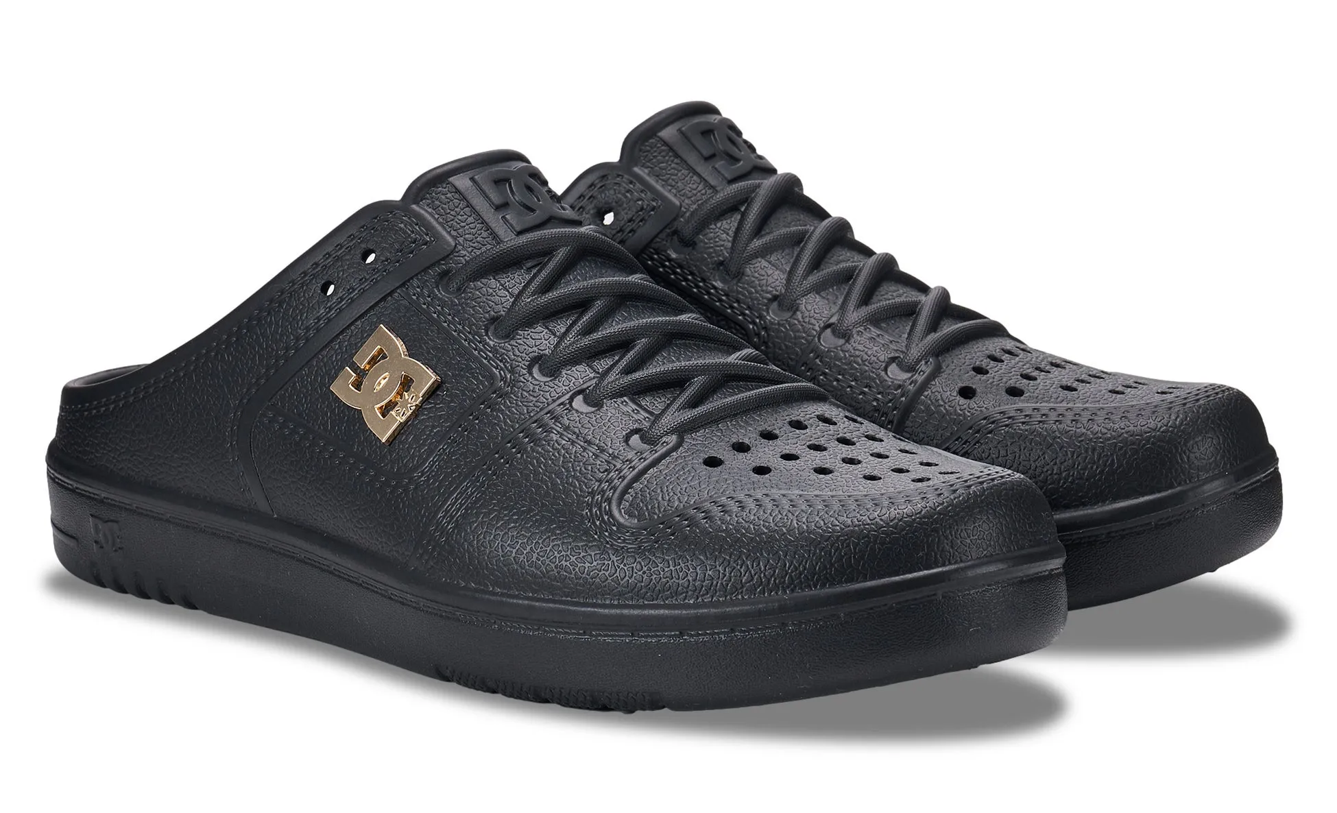 DCシューズの黒いミュールスニーカー。レースアップデザインでありながら踵がないスリッポンタイプで、全体的に凹凸のあるテクスチャが特徴です。つま先部分には通気孔があり、サイドにはゴールドのDCロゴがあしらわれています。