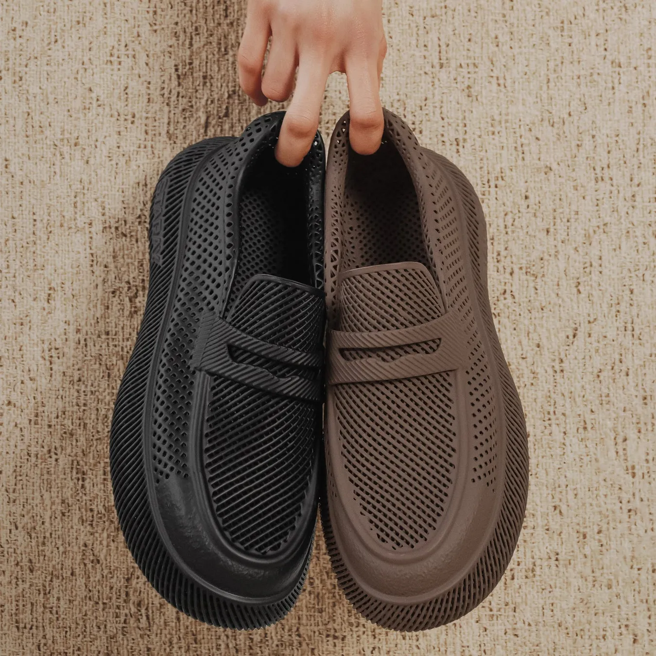 手で持たれた黒と茶色のスリッポンシューズのクローズアップ