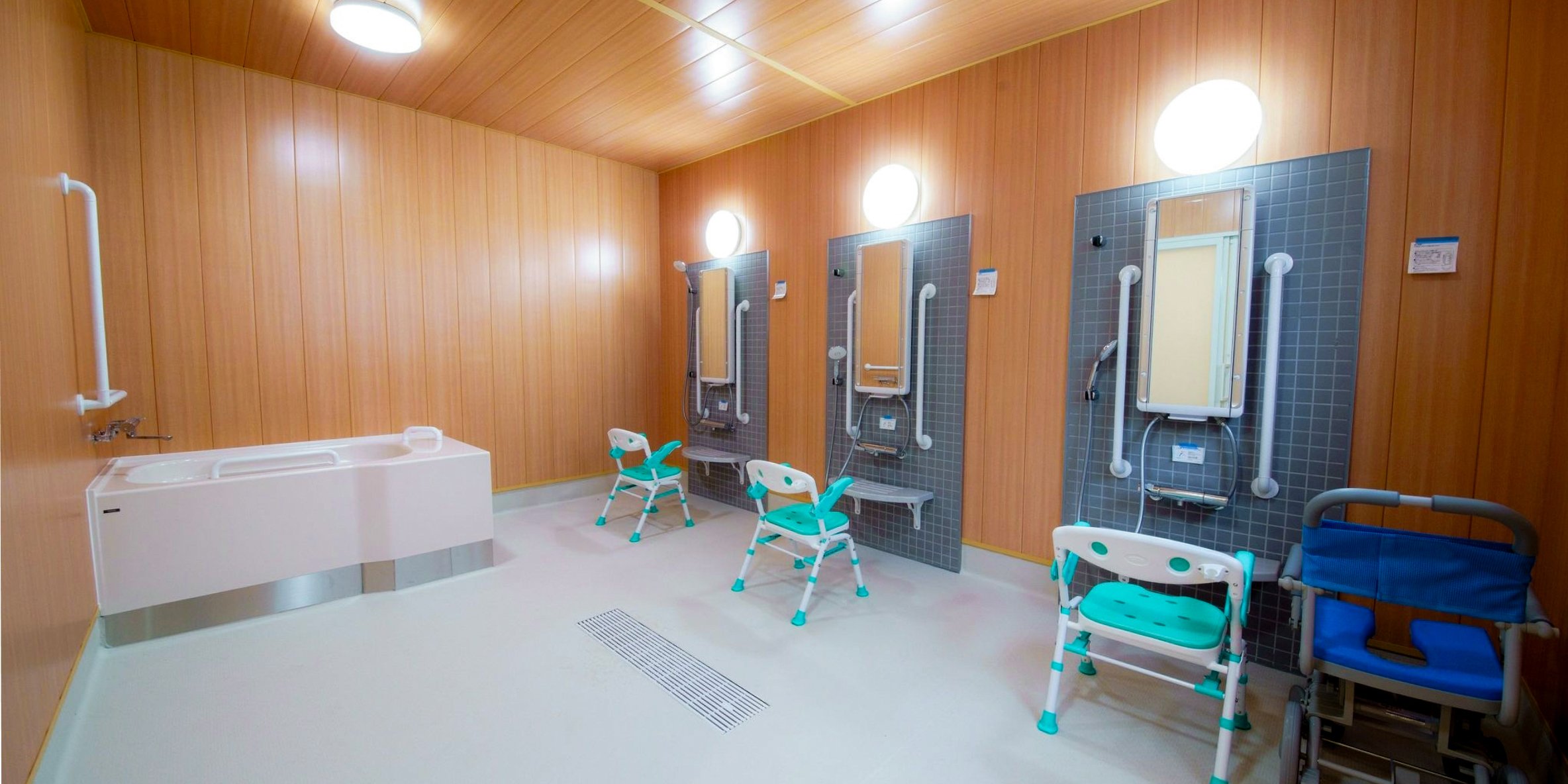 3台のボディハグシャワーが並ぶ浴場。シャワーチェアに腰かけた利用者は慣れた手つきでシャワーの準備に取りかかる