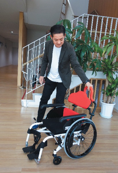車いす中央に介助バーを備え、力が伝わりやすい。横から利用者の顔を見ながら介助できる