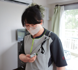 左肩のループにヒモを通すことで、屈んだ際に利用者の顔に当たるのを防ぐ（ライトグレー色）