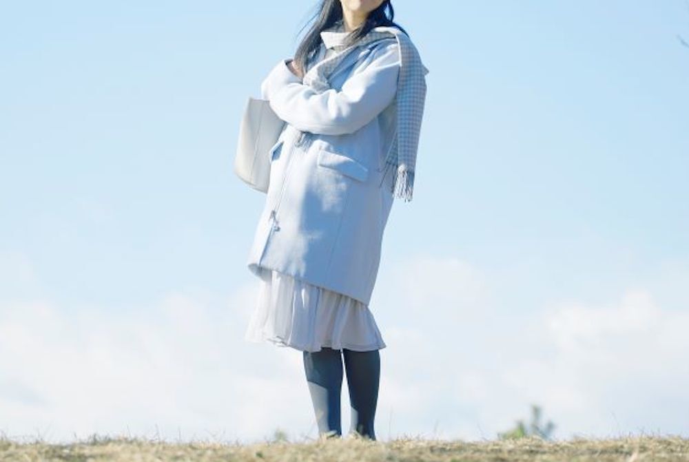くすみブルーのコートを着た女性