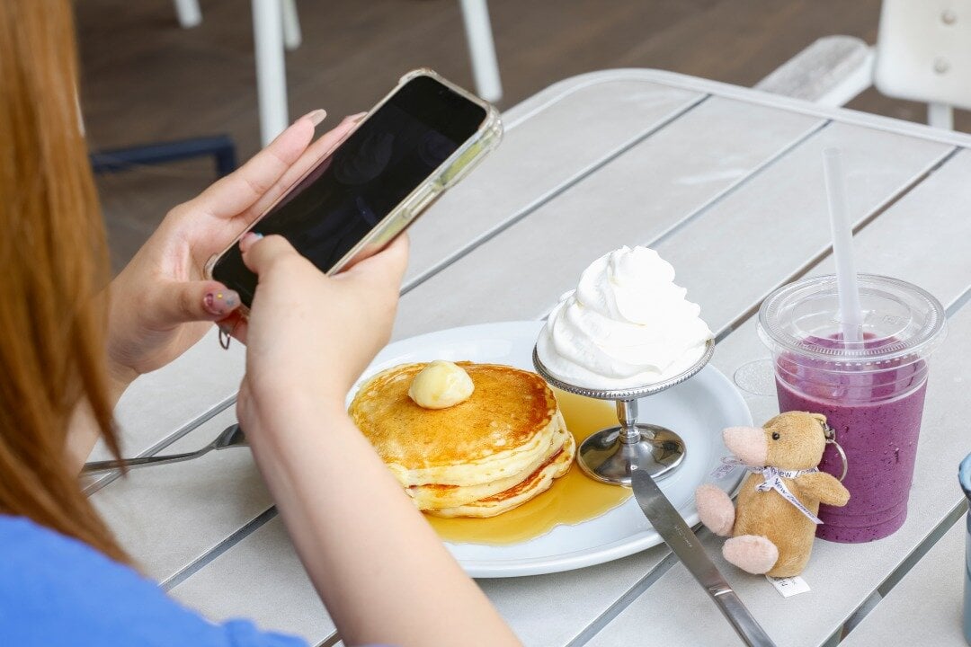 クラシックパンケーキの写真を撮る女性