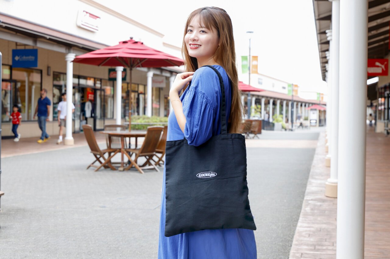 トートバッグを持った青いワンピースの女性