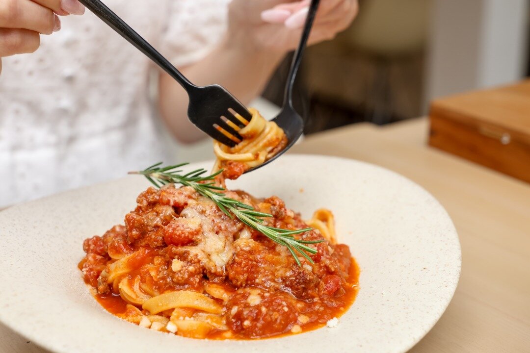 「阿智村特産の鹿肉のボロネーゼ」を食べる手