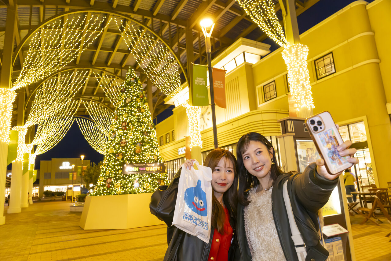 クリスマスツリーの前で写真を撮る女性