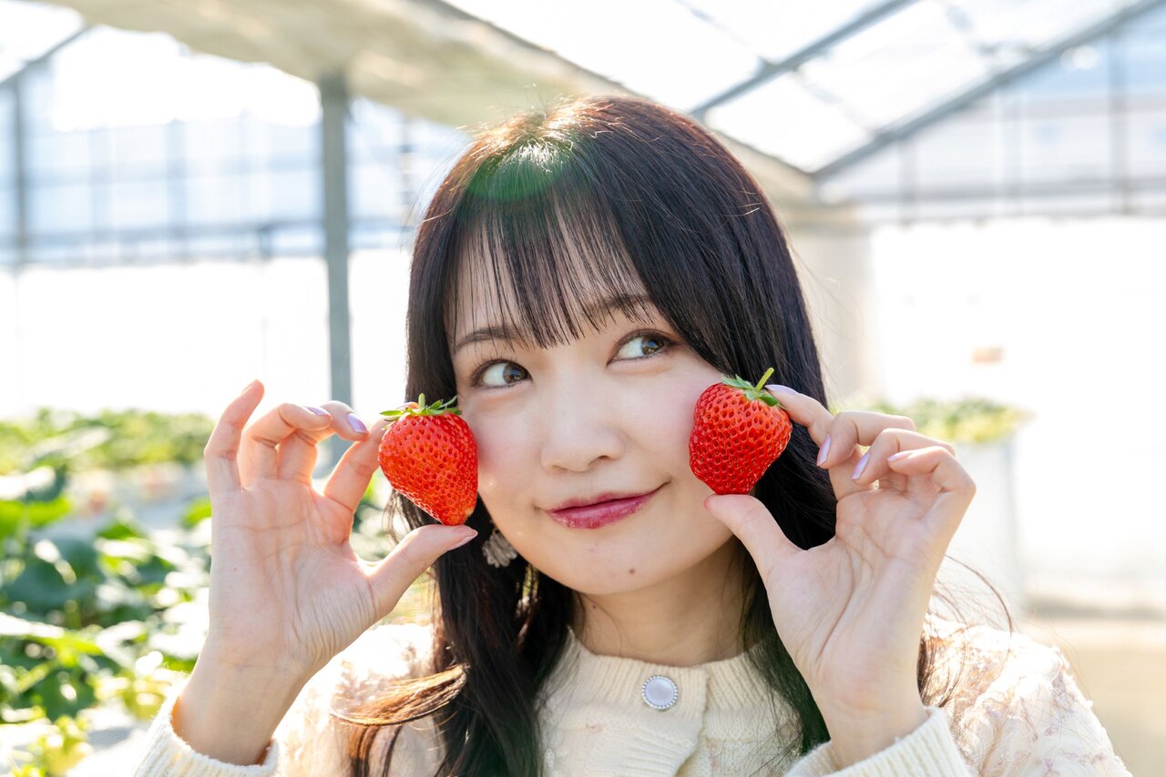 いちごを頬にあてる女性