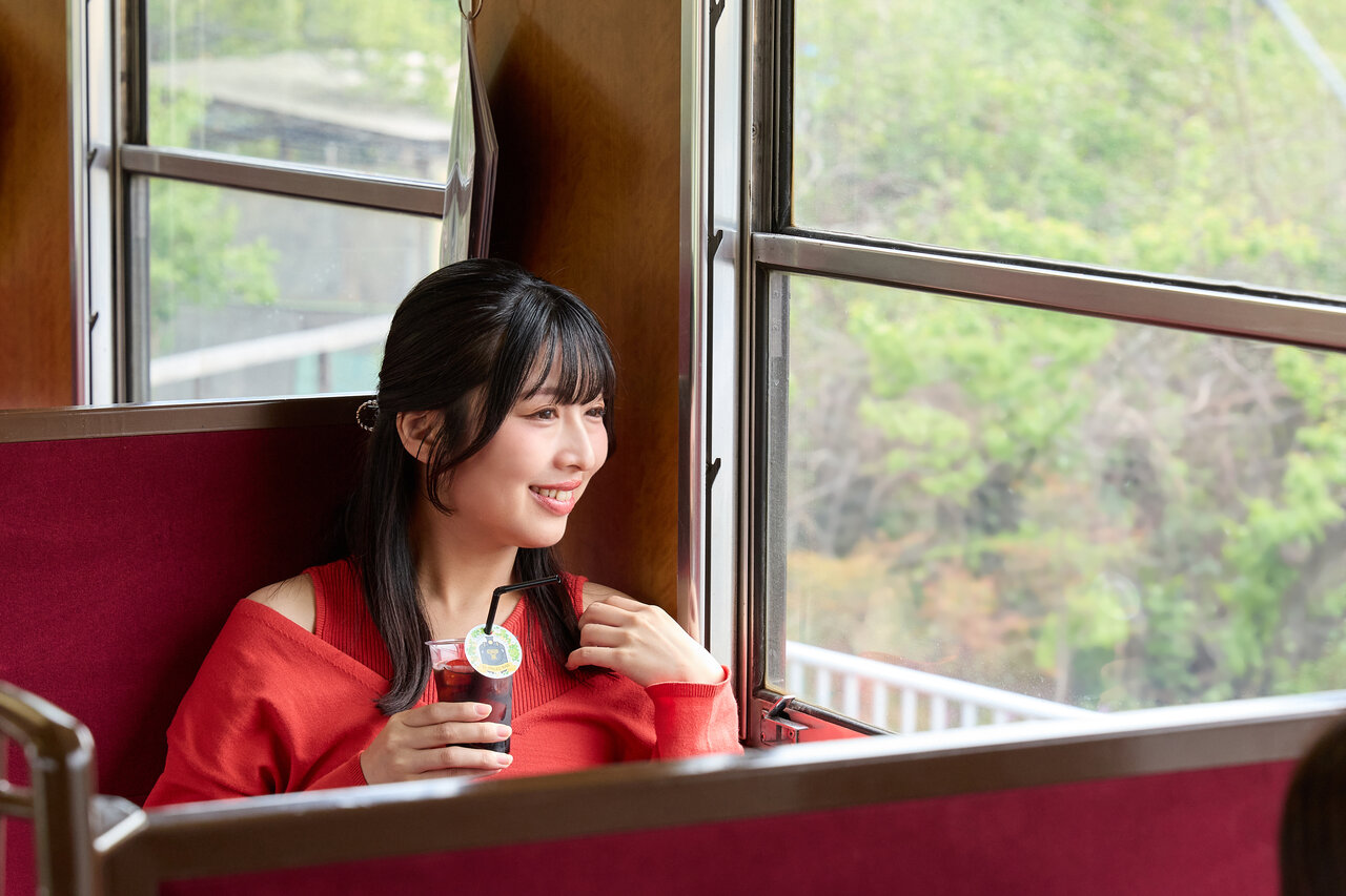 ドリンクを飲みながら車窓を眺める女性