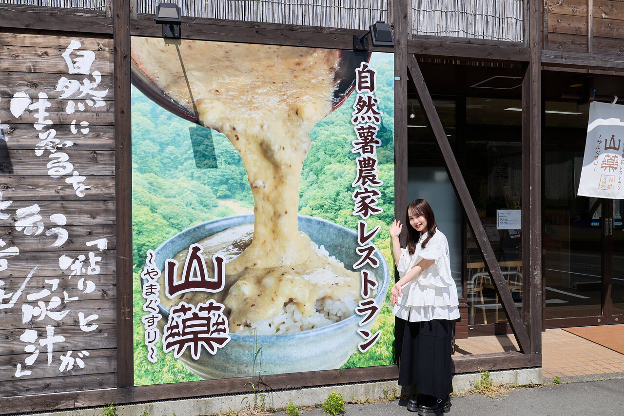 山薬の看板前に立つ女性
