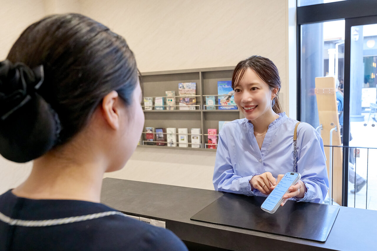 スマホの画面を見せる女性