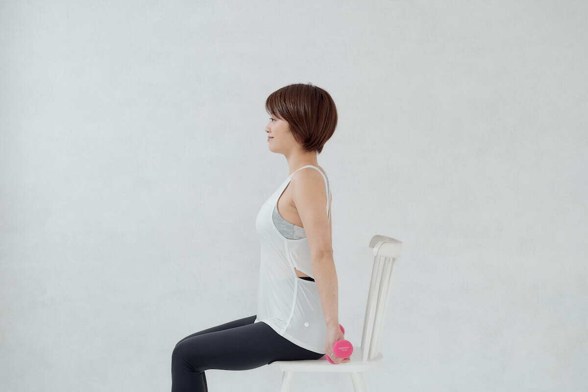 椅子に座ってウエイトを持つChiekoさん