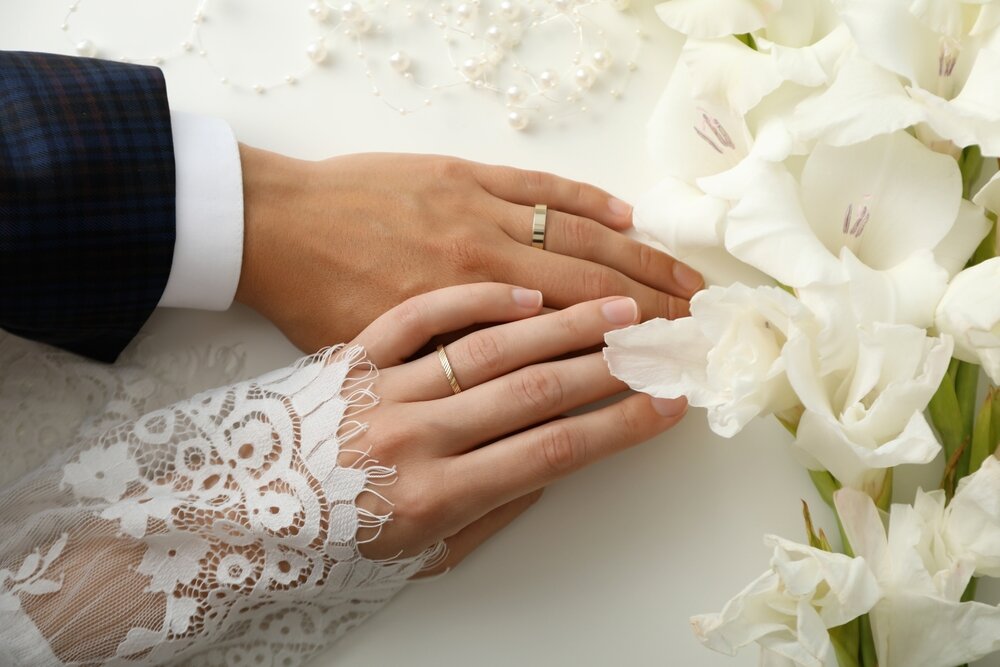 左手の薬指に結婚指輪を着けているカップル