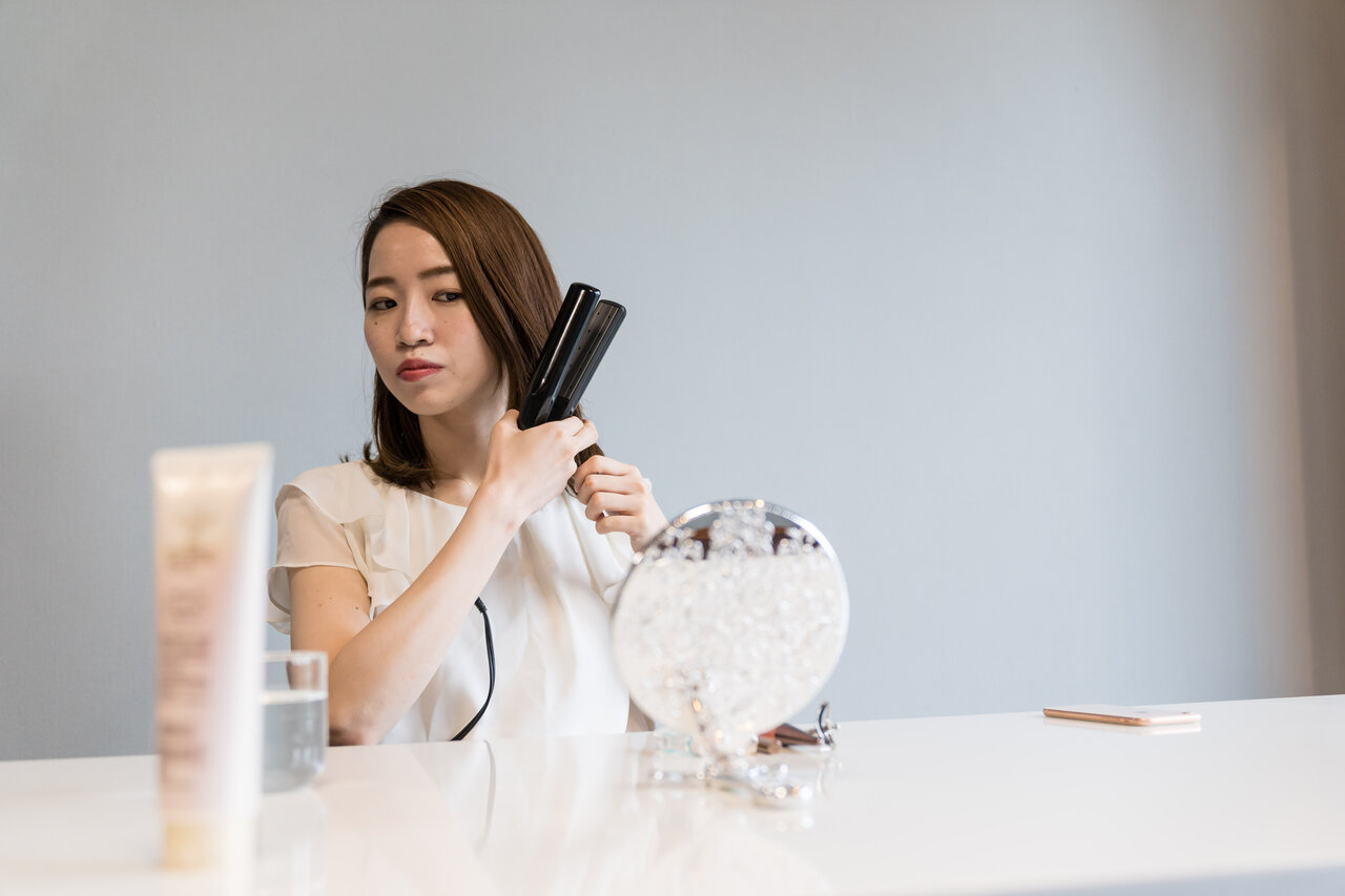 ヘアアイロンを使う女性