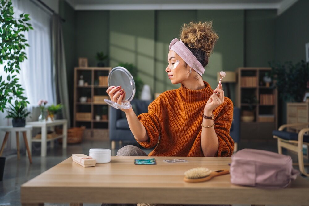 鏡を持ってクリームを塗っている女性の写真